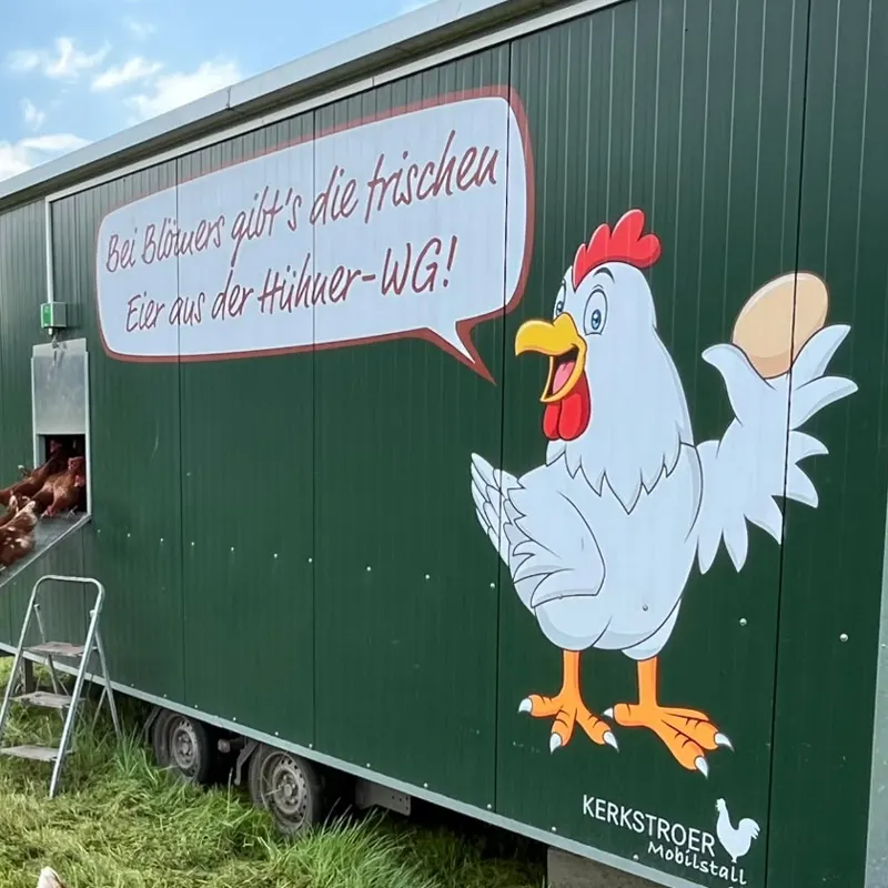 Grüner Stallwagen mit gemaltem Huhn und Sprechblase: „Bei Blömers gibt's die frischen Eier aus der Hühner-WG!“